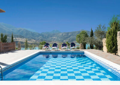 The swimming pool at El Dolmen de Alaju, El Gastor overlooks the surreal blue waters of Embalse de Zahara Lake